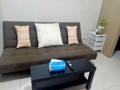 a living room with a brown couch and a table at La Maison Breeze Residence in Manila