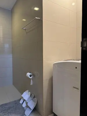 a bathroom with a shower and a toilet with white slippers at Landscape view and sea view 1BR near Airport in Manila