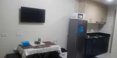 a kitchen with a refrigerator and a tv on the wall at La Maison Breeze Residence in Manila