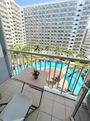 a balcony with a table and a view of a pool at Shell Residences MOA Prime - Paul in Manila