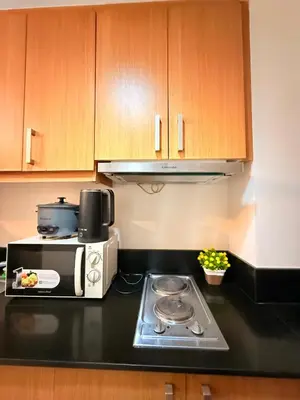 a kitchen with a microwave and a stove top oven at Shell Residences MOA Prime - Paul in Manila