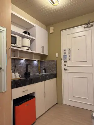 a kitchen with white cabinets and a white door at Bachelor's Crib-1 Alabang in Manila