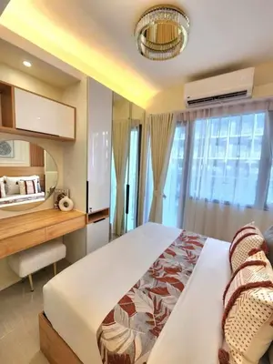 a bedroom with a large bed with a desk and a window at Exquisite space in Manila