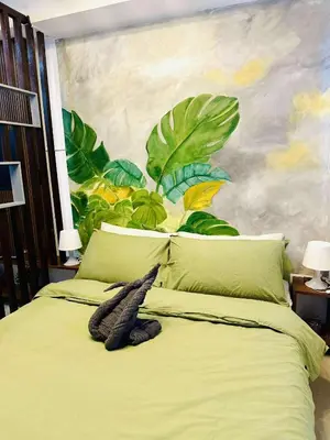a bedroom with a green bed with a painting on the wall at Minimalist Urban Loft in Manila