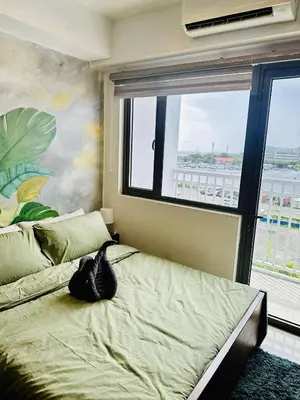 a cat sitting on a bed in a room with a window at Minimalist Urban Loft in Manila