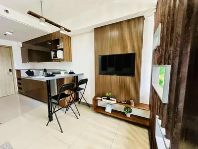 a kitchen with a table and a television in a room at Minimalist Urban Loft in Manila