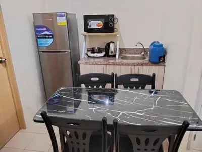 a kitchen with a table and a refrigerator at Angels Pad in Manila