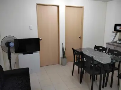 a dining room with a table and chairs and a television at Angels Pad in Manila