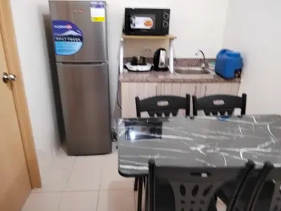 a table and chairs in a kitchen with a refrigerator at Angels Pad in Manila