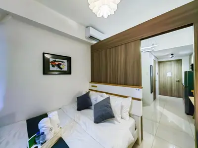 a bedroom with a white bed and a table at 1BR Condotel with Balcony at FAME Residences #FM08-1 in Manila