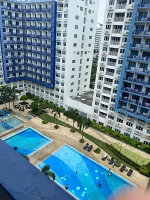 an overhead view of two swimming pools in front of tall buildings at Ennu staycation Near Moa in Manila