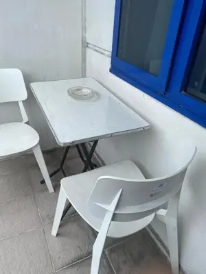 a white table and a chair next to a table and a window at Ennu staycation Near Moa in Manila