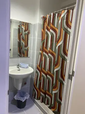 a bathroom with a shower curtain and a sink at Ennu staycation Near Moa in Manila