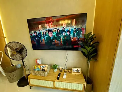 a flat screen tv hanging on a wall with a table at Netflix and WiFi Staycation Viceroy Walk to Venice Grand Canal in Manila