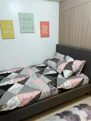 a bed with a comforter and pillows in a room at On The Shores - Staycation in Manila