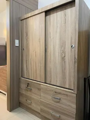 a large wooden cabinet with drawers in a room at On The Shores - Staycation in Manila