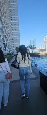 a woman standing on a sidewalk near the water at Coast Residences in Manila