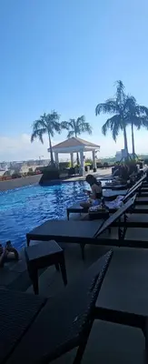 a row of chaise lounges on a beach with water at Coast Residences in Manila