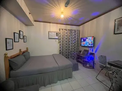 a bedroom with a bed and a television in it at Alabang Staycation Sucat in Manila