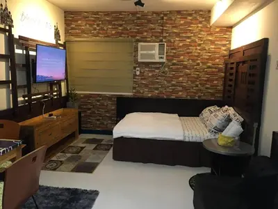 a bedroom with a bed and a brick wall at Alabang Staycation Sucat in Manila