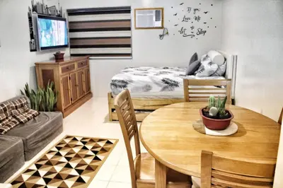 a living room with a table and a bed at Alabang Staycation Sucat in Manila