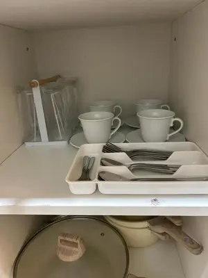 a white shelf with cups and plates on it at Vista gracia staycation in Manila