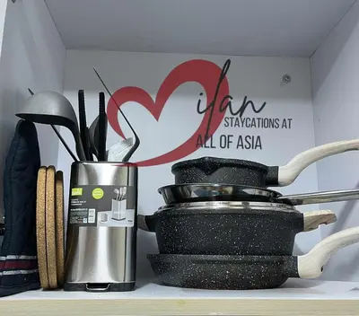 a shelf with pots and utensils in front of a sign at Mall of Asia Sea Residences- Milan Staycations Casa Juan in Manila