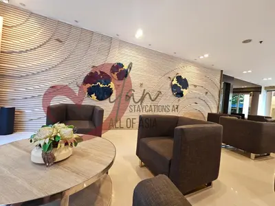 a lobby with chairs and a table and a wall at Mall of Asia Sea Residences- Milan Staycations Casa Juan in Manila
