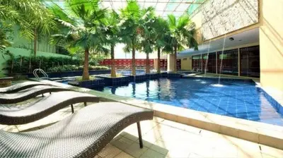 a large swimming pool in a building with palm trees at Cozy Condo near BGC and Ortigas with free Gym & Pool in Manila