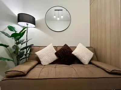 a living room with a couch with pillows and a mirror at MOA staycation located in Shore1 and 2 Residences Pasay City in Manila