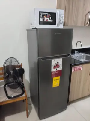 a microwave sitting on top of a refrigerator at MOA staycation located in Shore1 and 2 Residences Pasay City in Manila