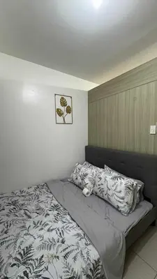 a bedroom with a bed with a gray blanket and pillows at MOA staycation located in Shore1 and 2 Residences Pasay City in Manila