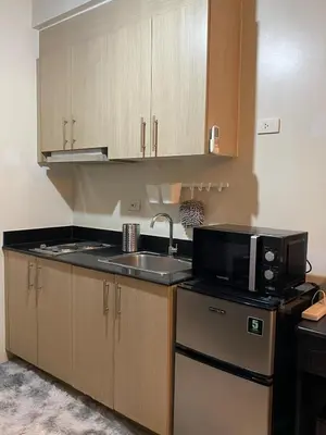 a kitchen with a sink and a microwave at Cozy Staycation in Pasay in Manila