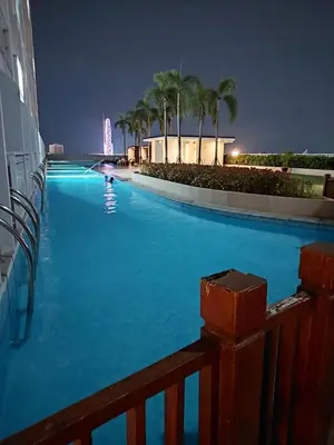 a large swimming pool at night with palm trees at Cozy Staycation in Pasay in Manila
