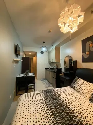 a bedroom with a large bed and a kitchen at Cozy Staycation in Pasay in Manila
