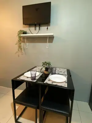 a black table with two chairs and a tv on a wall at Cozy Staycation in Pasay in Manila