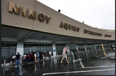 a man pulling a luggage cart in front of an airport at Mall of Asia Condohotel located in Shore Residences Pasay in Manila