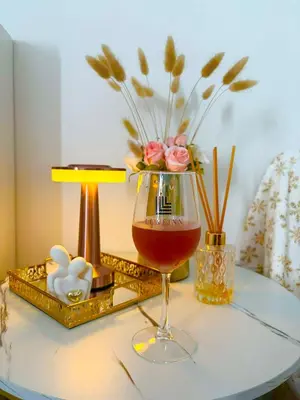 a glass of wine on a table with a vase of flowers at LuxeInn in Trece Martires