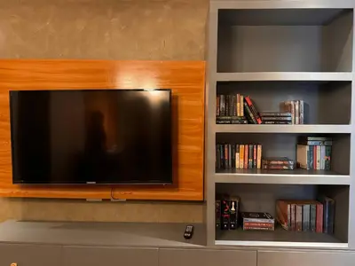 a flat screen tv in a living room with book shelves at 4BR Townhouse w Garage, Peaceful near Restaurants in Manila
