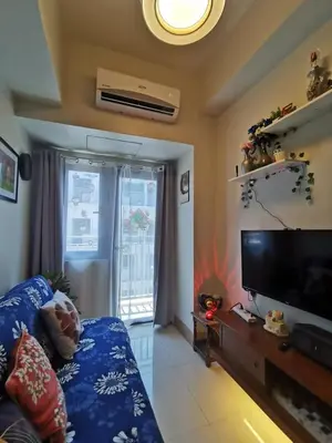 a living room with a couch and a television at Mall of Asia condotel shore 3 residence in Manila