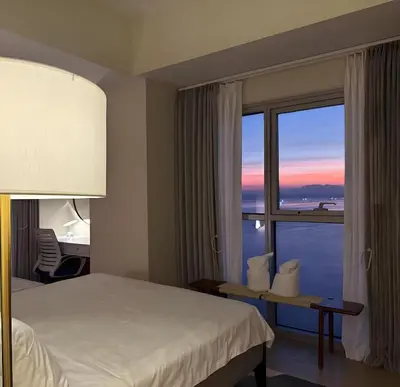 a hotel room with a bed and a window at Modern 1BR with Balcony Facing Infinity Pool Manila Bay Sunset Near Airports OKADA Solaire MOA in Manila