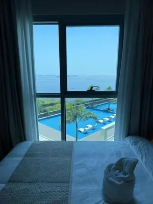 a bedroom with a large window with a view of a pool at Modern 1BR with Balcony Facing Infinity Pool Manila Bay Sunset Near Airports OKADA Solaire MOA in Manila