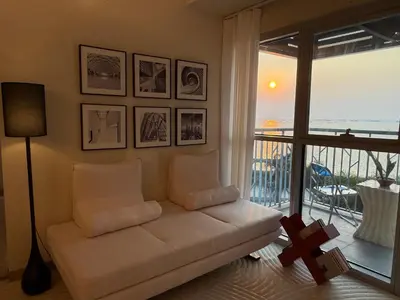 a living room with a couch and a large window at Modern 1BR with Balcony Facing Infinity Pool Manila Bay Sunset Near Airports OKADA Solaire MOA in Manila