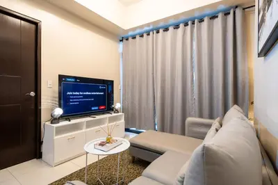 a living room with a couch and a tv at Florence Mc Kinley Spacious 2 Bedroom, 2 balcony nr Mall, T3 airport in Manila