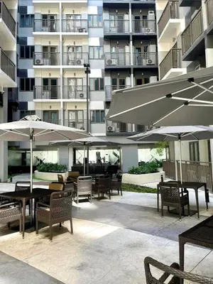 a patio with tables and umbrellas in front of a building at Apartment in Pasay, close to Mall Of Asia in Manila