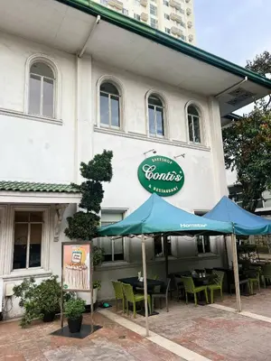 a restaurant with tables and umbrellas in front of it at High and Cozy Vista Shaw in Manila