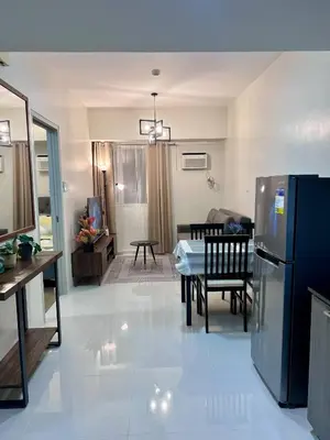 a kitchen and living room with a table and a refrigerator at High and Cozy Vista Shaw in Manila