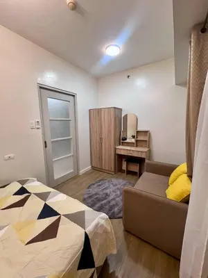 a bedroom with a bed and a couch and a desk at High and Cozy Vista Shaw in Manila