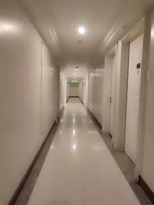 a long hallway with white walls and a long white floor at BP1637 Facing Pool with Balcony near MOA BP1637 in Manila