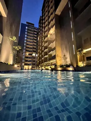 a large swimming pool in a city at night at Lovely 1BR w Sunset near Solaire, Okada, Airport in Manila